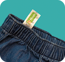 A stick-on name label applied to the care label of a school jumper